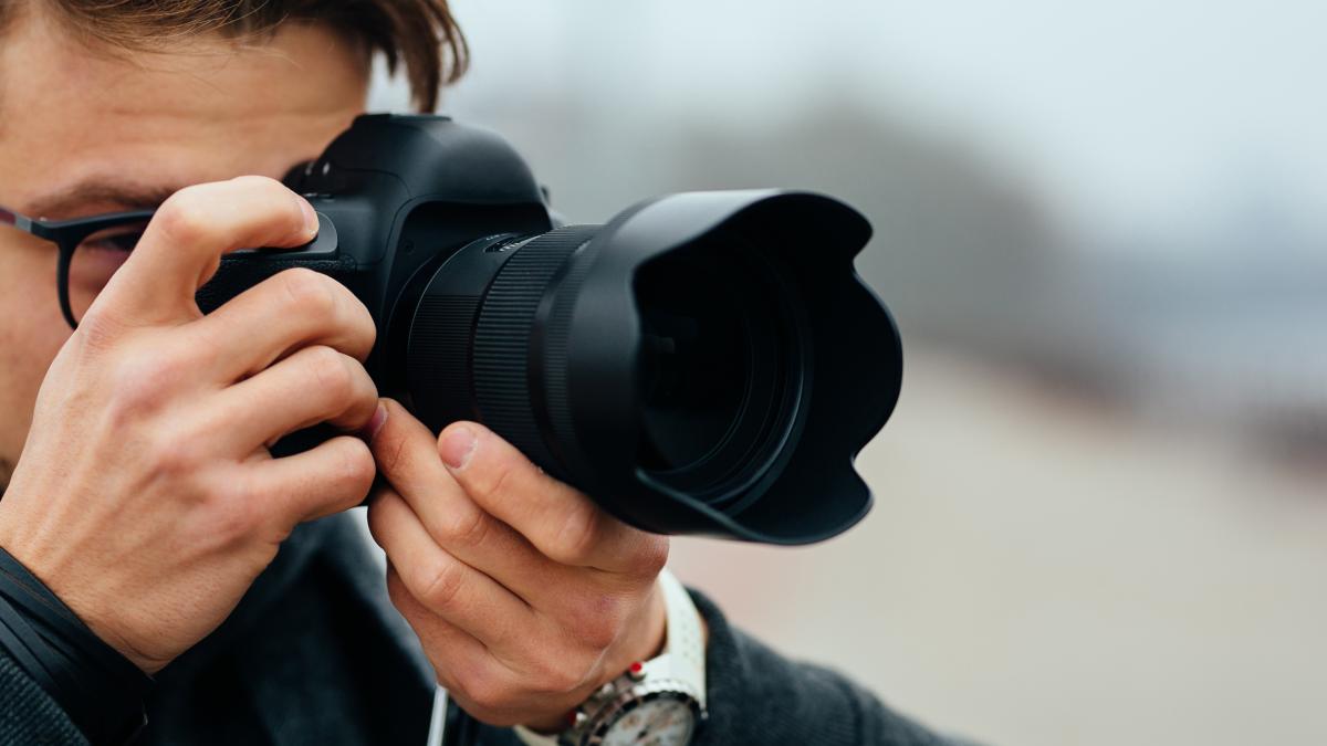 detail_view_young_man_eyeglasses_taking_photos_street