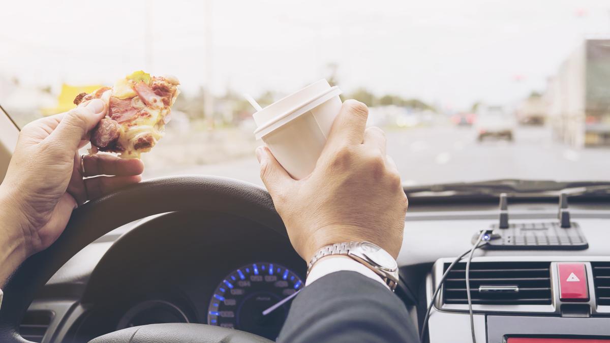 man-eating-pizza-coffee-while-driving-car-dangerously