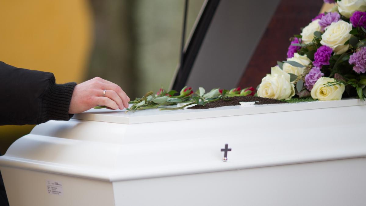closeup-shot-person-hand-casket-with-blurred-background