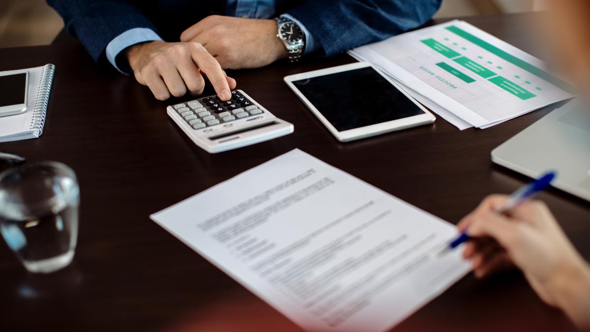 closeup-real-estate-agent-using-calculator-while-his-client-is-signing-contract