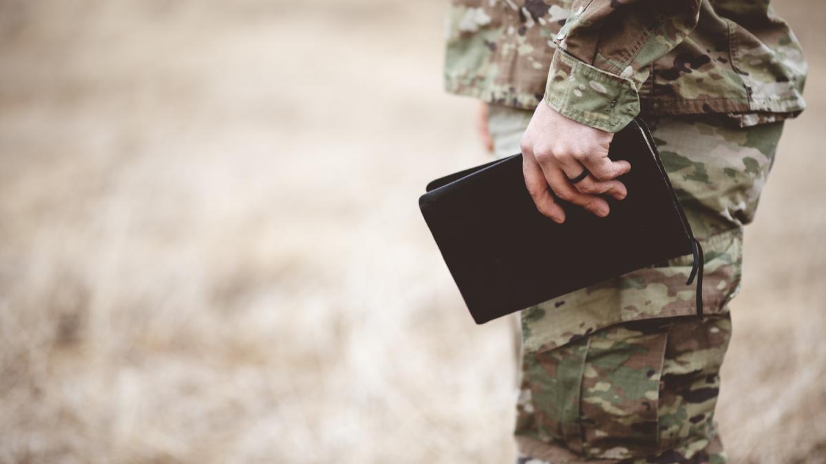 shallow-focus-shot-young-soldier-holding-bible-field