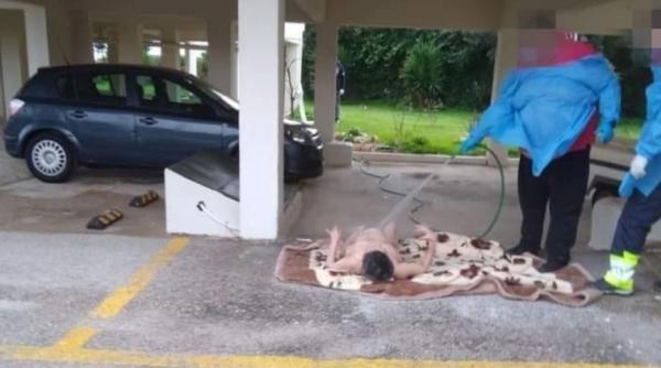 Imaginea care a stârnit furie și neputință: Bătrână spălată cu furtunul în mijlocul străzii de către personalul medical, în Grecia